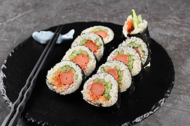 Korean Roll Gimbap (Kimbob oder Kimbap) aus gedämpftem weißem Reis (Bap) und verschiedenen anderen Zutaten wie Kyuri, Karotte, Wurst, Krabbenstäbchen oder Kimchi und umwickelt mit Seetang Laver