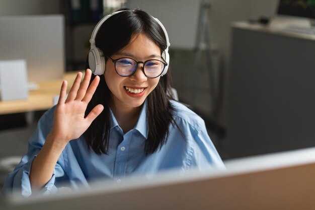 Koreanische Geschäftsfrau Videoanrufe auf dem Computer winken Hallo im Büro