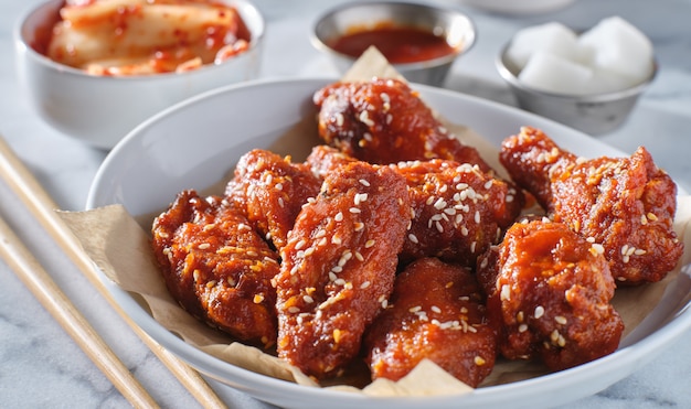 Koreanische Hühnerflügel in Gochujang-Sauce mit Kimchi und eingelegtem Rettich