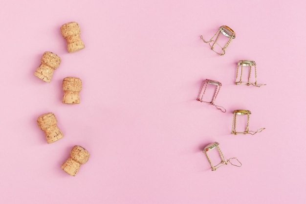 Korken und Muscheln aus Champagner-Sekt auf rosa Hintergrund mit Kopienraum. Weihnachts- und Neujahrskonzept. Flach liegen.