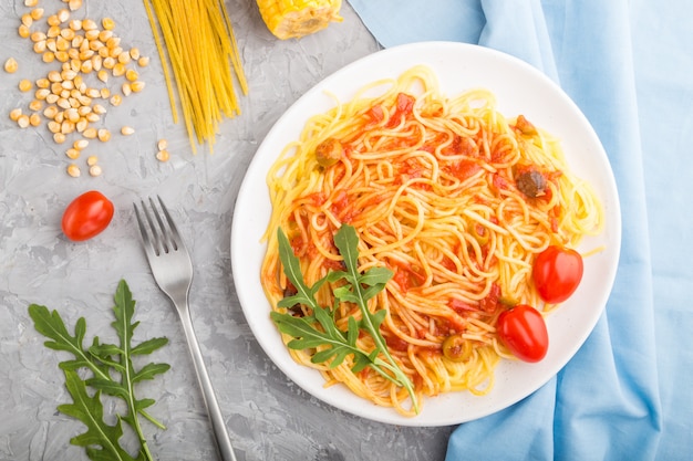 Kornnudeln mit Tomate auf grauem Betonhintergrund