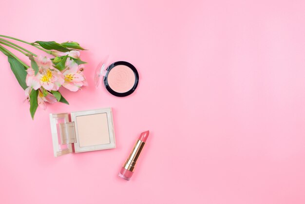 Kosmetik und Blumen auf einem rosa Hintergrund