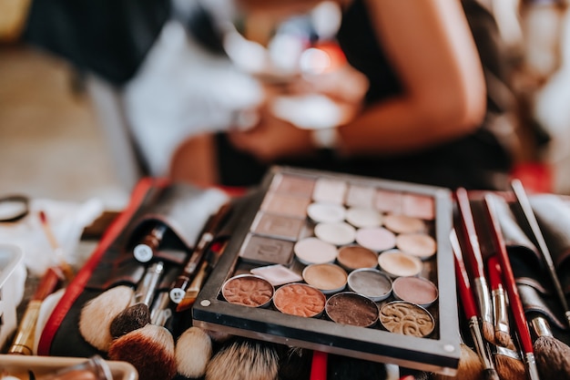 Kosmetik- und Make-up-Pinsel liegen während der Arbeit der Visagistin