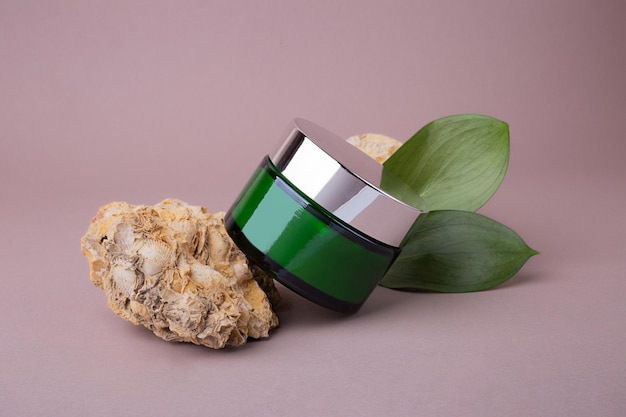 Kosmetikbehälter aus grünem Glas auf Podest aus Naturstein, umweltfreundliches Konzept