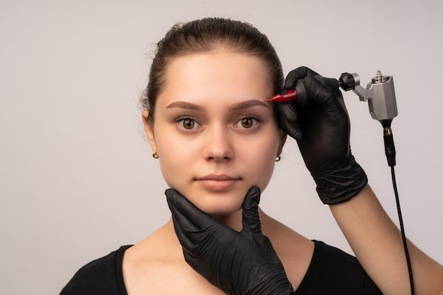 Foto kosmetikerin, die permanentes make-up auf die augenbrauen aufträgt.