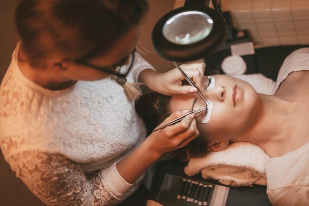 Kosmetikerin, die verlängerte Wimpern anwendet, um im Schönheitssalon zu modellieren.