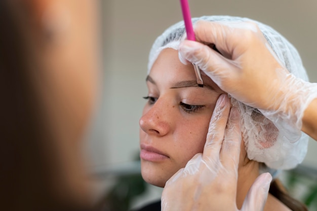 Kosmetikerin führt ein Microblading-Verfahren an einer Frau durch
