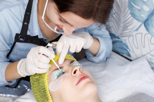 Kosmetikerin macht Laminierung von Wimpern zu einer Frau Wimpernlaminierung Wimpernverlängerungen