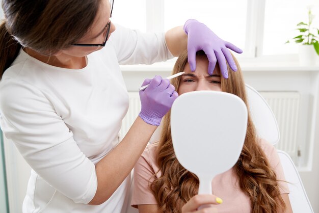 Kosmetikerin mit Gesichtsmarker auf dem Gesicht der Patientin vor der Schönheitsbehandlung im Spa-Salon-Client