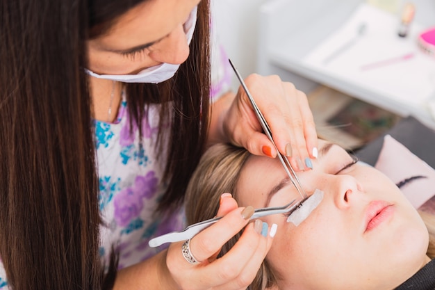 Kosmetikerin repariert die Wimpernverlängerung einer Frau