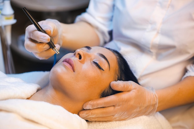 Kosmetikerinhände machen Mesotherapie-Injektion mit Dermapen auf dem Gesicht der Kunden in der Spa-Salonkosmetik...