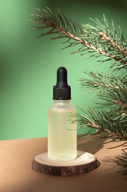 Kosmetische Flasche mit ätherischem Öl auf grünem Tannenbaumhintergrund Schönheitsprodukt für die Gesichtspflege Flasche für das Branding von Medizin oder Kosmetik Natürliche Bio-Kosmetik