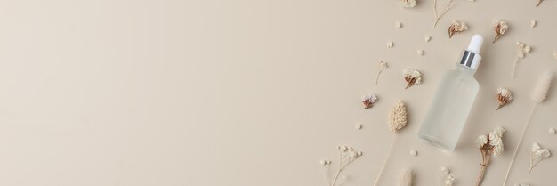 Kosmetische Flasche mit Blumen auf pastellbeige Hintergrund Flach gelegener Kopierraum
