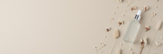 Kosmetische Flasche mit Blumen auf pastellbeige Hintergrund Flach gelegener Kopierraum