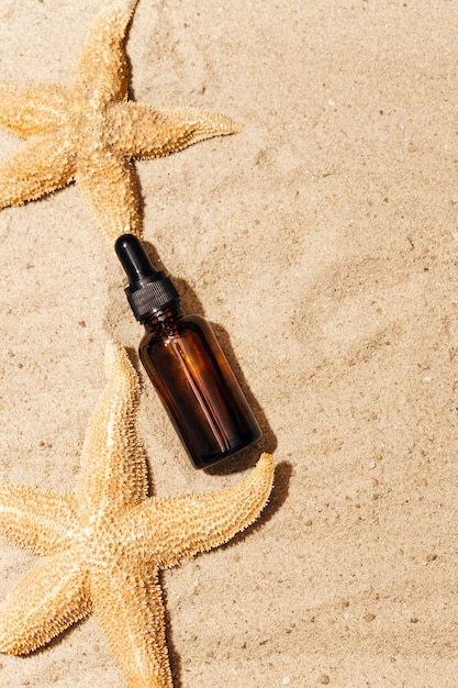 Kosmetische Flasche mit einer Pipette auf dem Sand. vor dem Hintergrund von Sand.