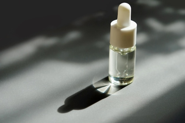 Kosmetische oder medizinische Glasflasche mit Pipette Hautpflegekonzept Natürliches hartes Licht tiefe Schatten