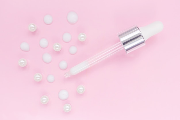 Kosmetische pipette mit serum auf rosa