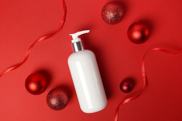 Foto kosmetische produktlotion oder duschgel auf rotem weihnachtshintergrund. körperpflegeprodukte für den winter