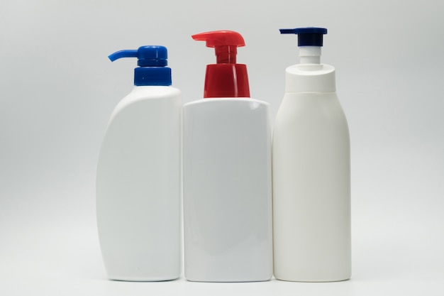 Kosmetische weiße Plastikflasche mit dem blauen und roten Pumpenspender lokalisiert auf weißem Hintergrund mit leerem Aufkleber- und Kopienraum. Hautpflegeflasche. Körperpflegelotion. Kosmetikdose Paket. Shampoo-Flasche.