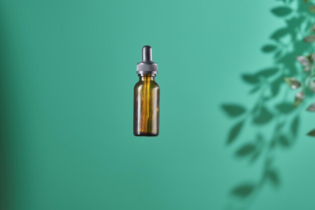 Kosmetisches Produkt in Röhrenglasflasche Lotion Anti-Aging-Feuchtigkeitscreme ätherisches Öl oder Serum für das Gesicht auf grünem Hintergrund mit heller Schattennatur Bio-Natur- und Beauty-Hautpflegekonzept