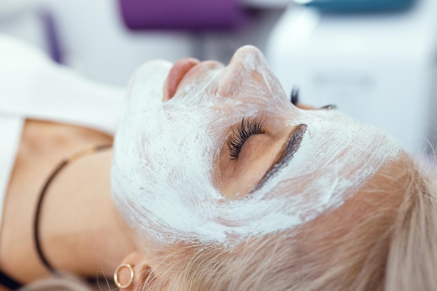 Kosmetologe, der im Spa-Salon eine Maske auf das Gesicht des Kunden aufträgt