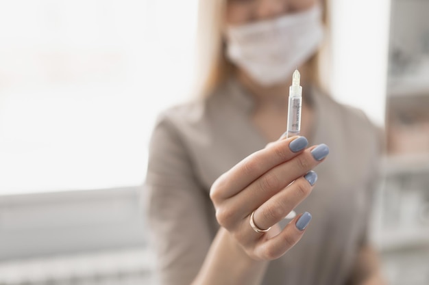 Kosmetologe hält in der Hand und zeigt eine Spritze mit einer kleinen Nadel für Eingriffe
