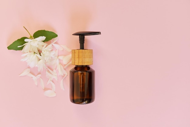 Kosmetologie, Behandlung, Schönheit, natürliches Bio-Kosmetikprodukt in Flasche mit Jasminblüten auf rosa Hintergrund, Draufsicht