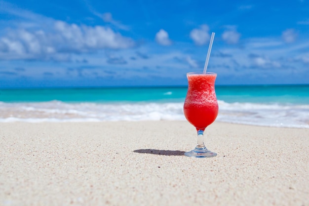 Foto kostenloser foto-smoothie im strandsand mit blauem wolkenhintergrund