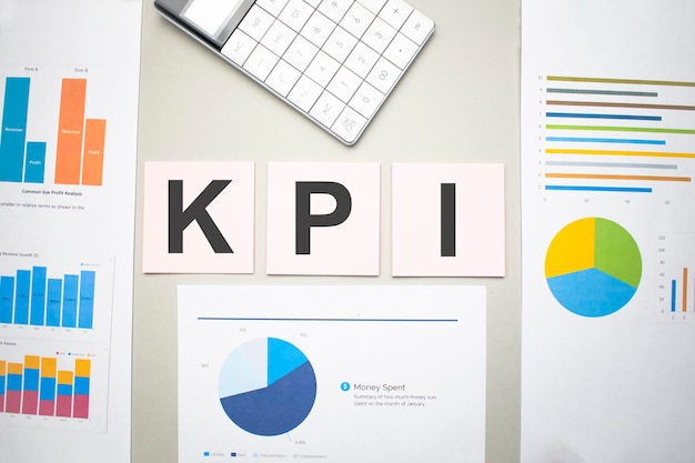 KPI empresarial, indicador clave de rendimiento, texto en las hojas de papel, gráficos y calculadora blanca