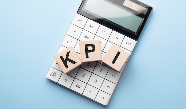 KPI, indicador-chave de desempenho para o conceito de objetivo da empresa, blocos de cubo construindo a sigla da palavra e calculadora