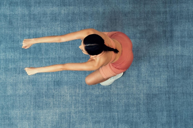 Kräftige, energiegeladene Frau macht zu Hause Sport. Junge athletische asiatische Frau trainiert Kraft und Ausdauer als Heimtrainingsprogramm mit Kniebeugen