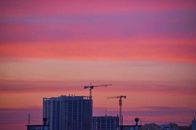 Kräne auf einer Baustelle bei Sonnenuntergang