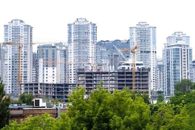 Kräne auf einer Baustelle des Gebäudes des modernen Wohnviertels Hohe Mehrfamilienhäuser oder Wolkenkratzer in einem neuen Elite-Komplex.