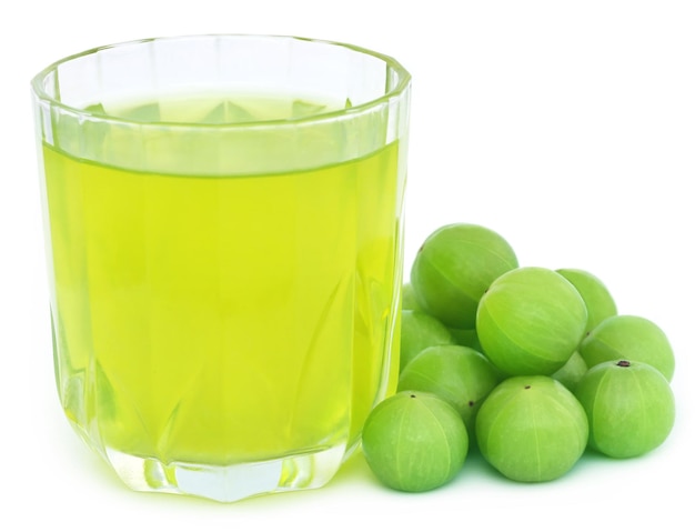 Kräuter-Amla-Saft mit frischen Früchten auf weißem Hintergrund