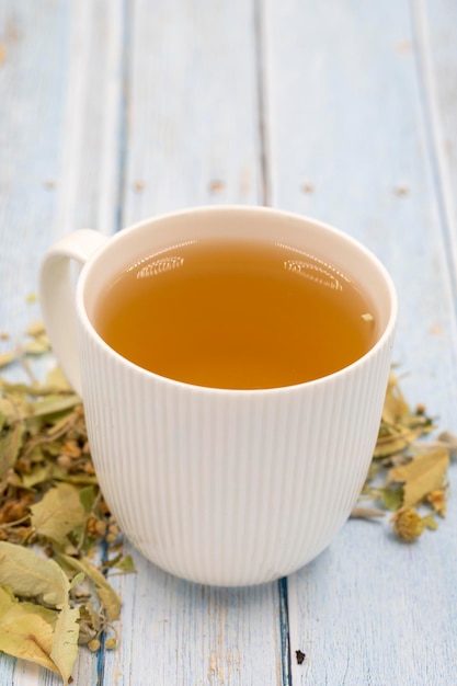 Kräutertee auf blauem Holz Hintergrund Lindentee immunstärkender Kräutertee Medizinischer Tee aus Lindenblättern Nelkenpartikel und Kamille