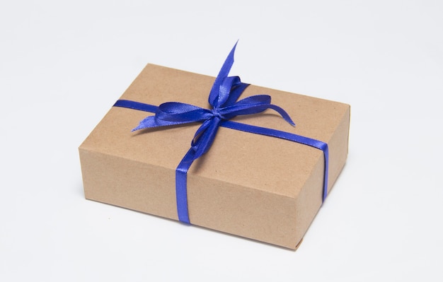 Kraft-Geschenkbox mit blauem Band ist auf weißem Hintergrund.