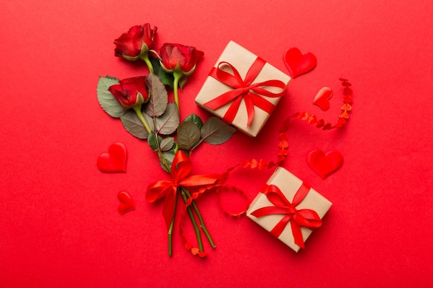 Kraft-Geschenkbox mit schönem rotem Band und Rosenkonzept des Valentinstag-Jubiläums-Muttertages und der Draufsicht des Geburtstagsgruß-Kopienraums