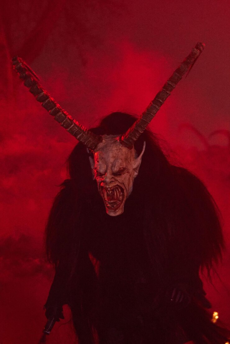 Foto krampus vestido com máscaras misteriosas iluminadas por um fogo na noite
