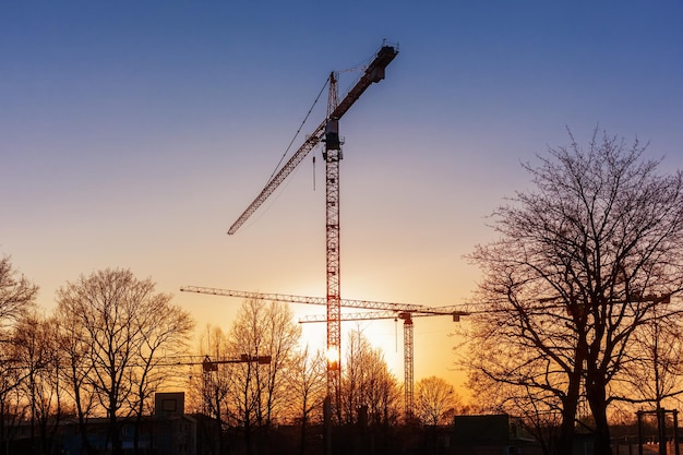 Kran auf der Baustelle am Sonnenuntergang Krane Silhouette Tower Crane Gebäude neues Wohngebiet