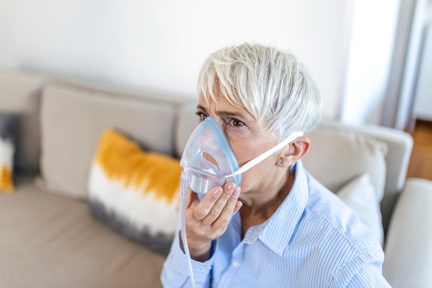 Kranke ältere Frau beim Einatmen von Sauerstoffmasken, Lungenentzündung Coronavirus-Pandemie. Kranke ältere Frau, die eine Sauerstoffmaske trägt und sich einer Behandlung unterzieht. ältere Frau mit Covid 19