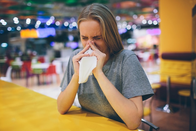 Kranke Frau, die ihre Nase in ein Taschentuch putzt