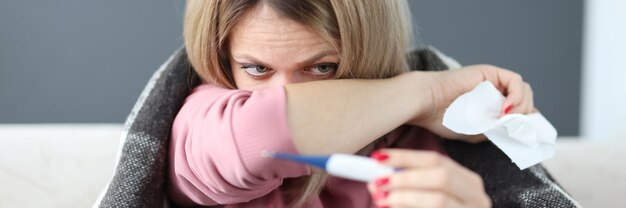 Kranke Frau mit Thermometer und Papierserviette unter Abdeckungen Isolierung von Patienten mit