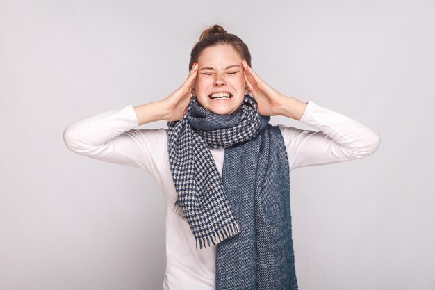 Kranke Frauen haben Kopfschmerzen, halten den Kopf und schreien. Studioaufnahme, isoliert auf grauem Hintergrund