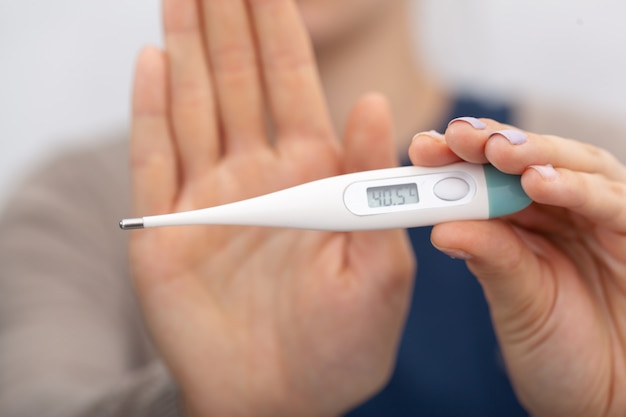 Kranke Frauen mit einem Thermometer