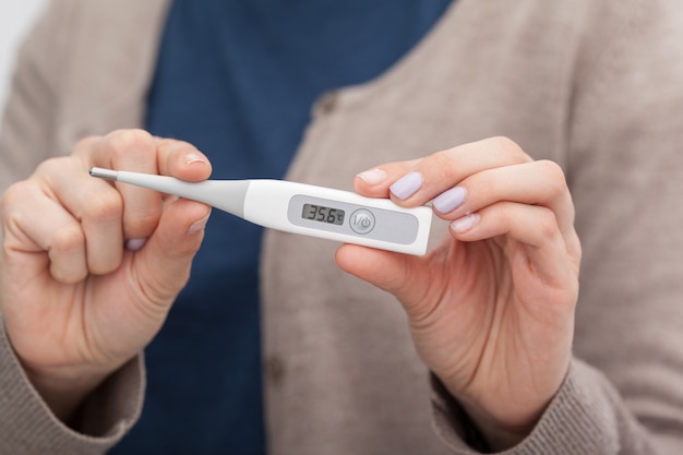 Kranke Frauen mit einem Thermometer