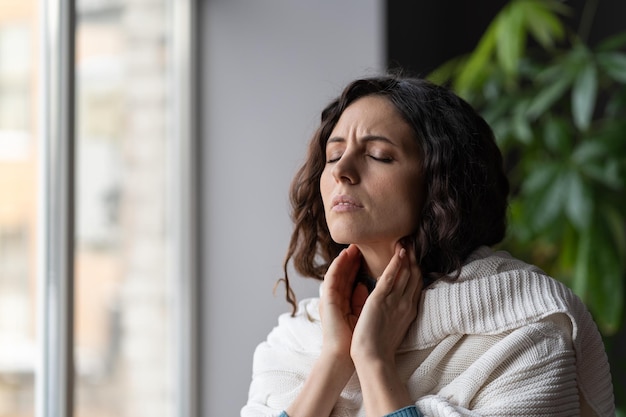 Kranke Frauen mit Halsschmerzen berühren vergrößerte Lymphknoten und leiden an Covid-Angina oder Pharyngitis