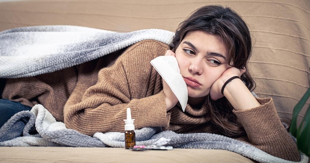 Kranke junge Frau mit Medikamenten liegt im Bett, Erkältung und Heimbehandlung