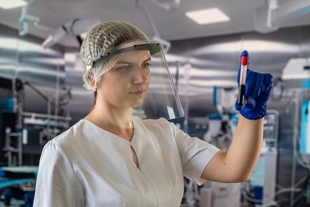 Krankenschwester Arzt in Schutzuniform Handschuh und Maske betrachtet Blutproben im Operationskrankenhaus