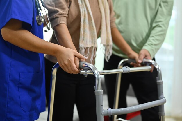 Krankenschwester, die älteren Frauen beim Gehen mit einem Gehwagen im Altersheim hilft Gesundheitsdienst und Rehabilitation