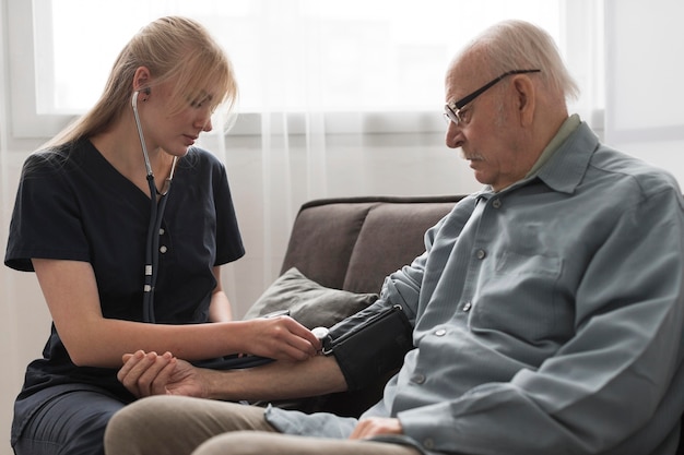 Foto krankenschwester, die den blutdruck des älteren mannes überprüft